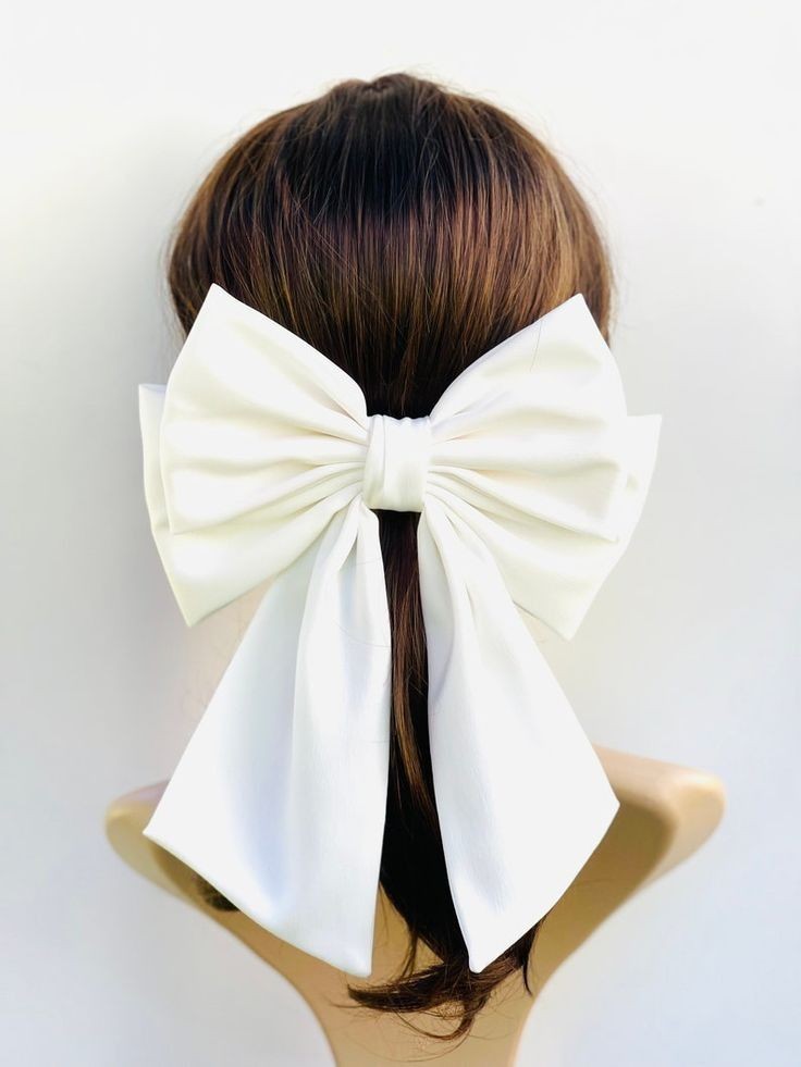 Back view of a woman's head with brown hair, adorned with a large white bow.